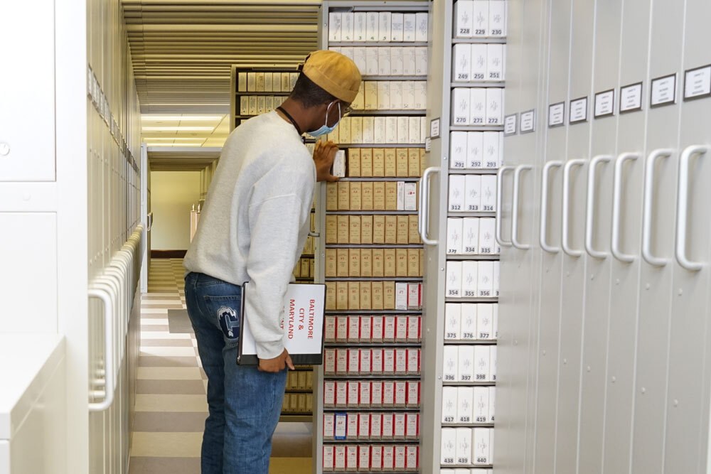a person looking at boxed microfilm reels in the Periodicals Department