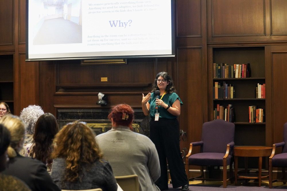 photo from a SLRC conference showing a person speaking, audience, and screen in the Central Library's Poe Room