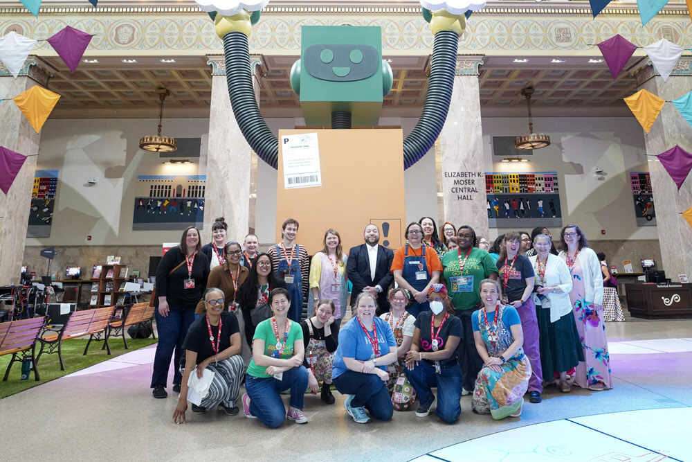 Pratt Library staff in Central Library hall with a giant robot and kite decorations during a children's festival
