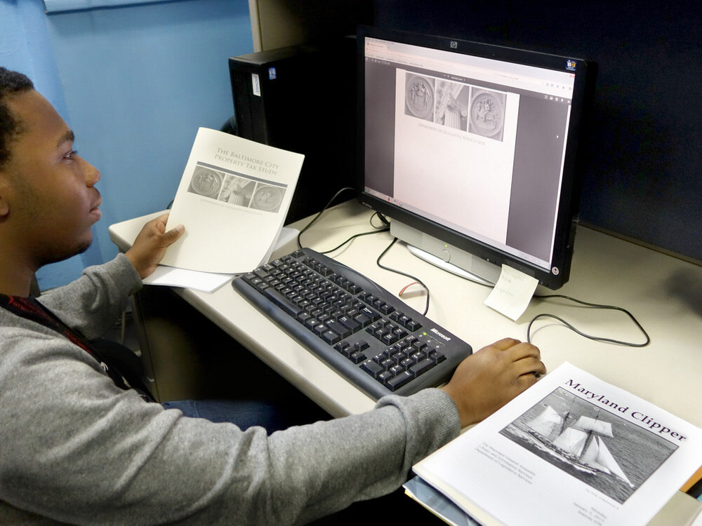 Pratt Library staff viewing a paper and digitized version of state documents